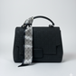 Black textured handbag with a patterned strap on a white background