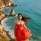Woman in a red dress standing on a coastal path with ocean and cliffs in the background